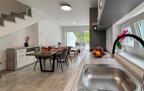Eine moderne Küche mit Essbereich, einer Edelstahl-Spüle und Blick ins Freie.