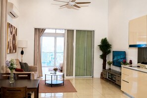 Una sala moderna con un sofá, una mesa de centro y un televisor. Hay una puerta corrediza de vidrio que da a un balcón.
