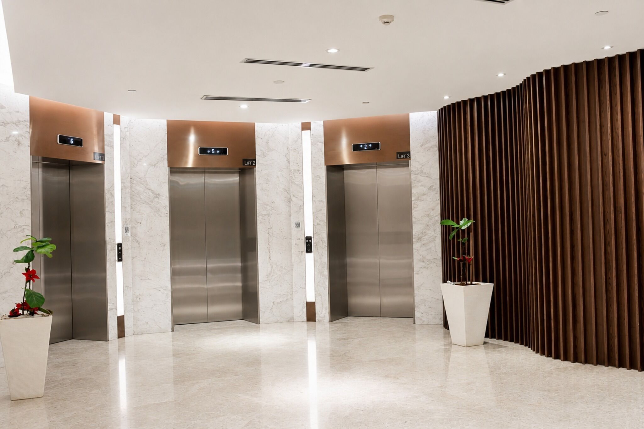 A modern elevator area with three elevators, each marked with a lift number.