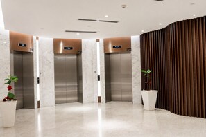 A modern elevator area with three elevators, each marked with a lift number. - Quill Residences KLCC by Moonlight (Kuala Lumpur)