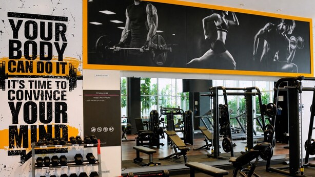 A gym with various exercise equipment, a wall with motivational text, and a window providing natural light. - Quill Residences KLCC by Moonlight (Kuala Lumpur)