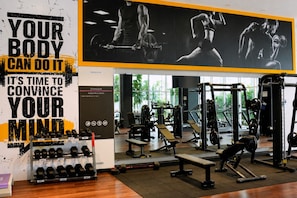 A gym with various exercise equipment, a wall with motivational text, and a window providing natural light. - Quill Residences KLCC by Moonlight (Kuala Lumpur)