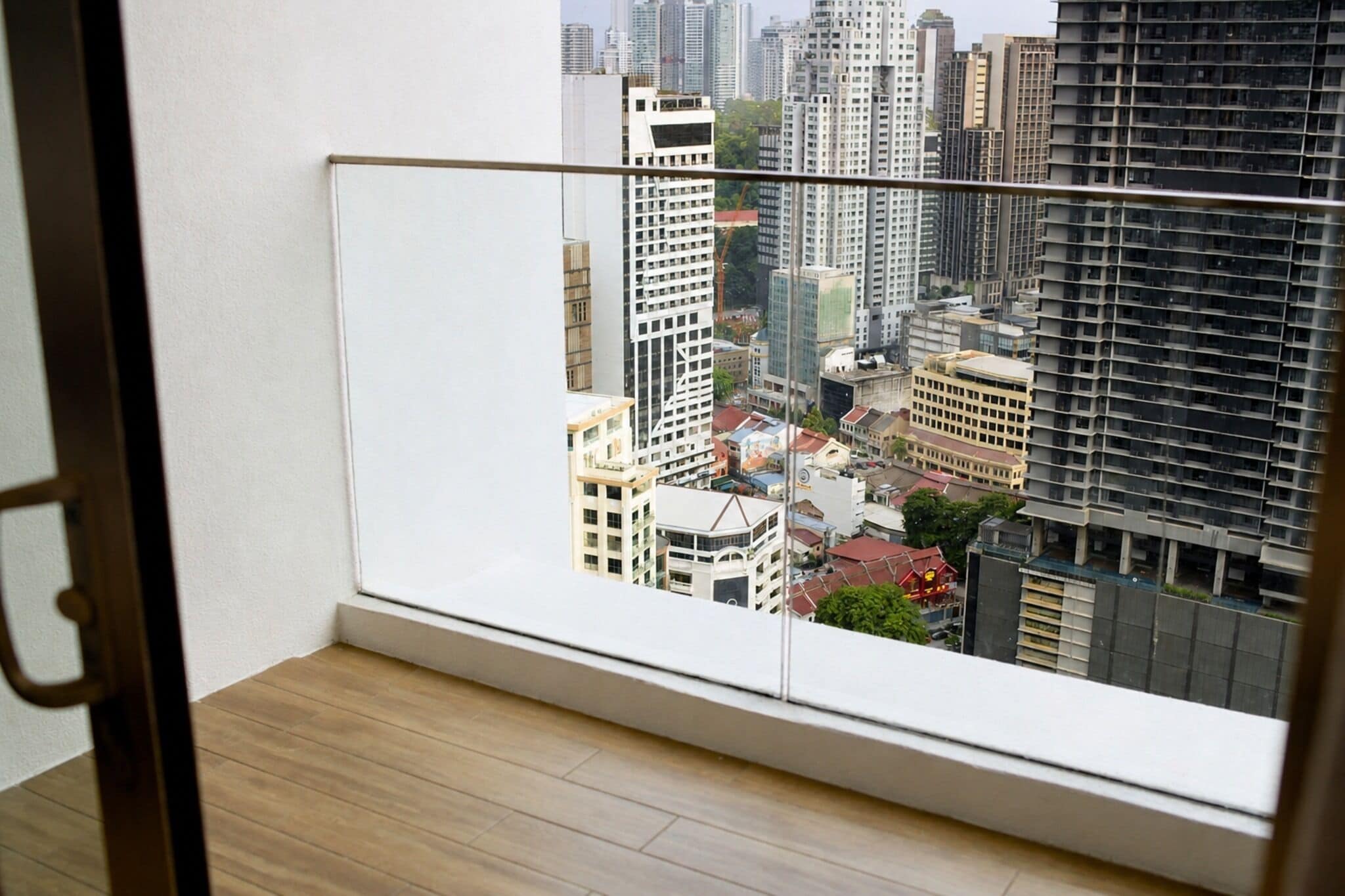 A room with a view of a cityscape through a window with a metal railing.