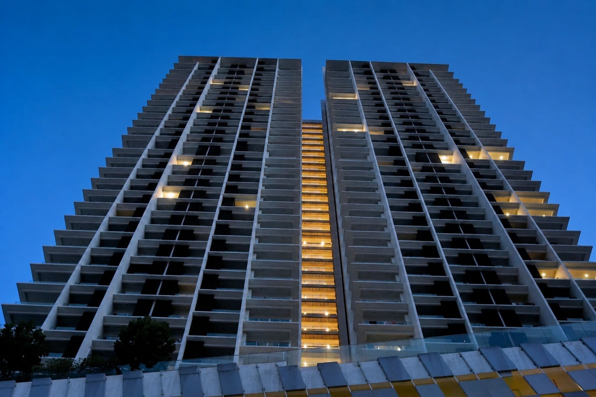 Un edificio de gran altura con un diseño arquitectónico moderno, que presenta una fachada simétrica con ventanas y balcones regularmente distribuidos.