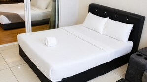 A bed with white bedding and a rolled towel, a black headboard, and a small bedside table with a lamp. - Quill Residences KLCC by Moonlight (Kuala Lumpur)