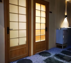 Una puerta de madera con paneles de vidrio satinado y una lámpara moderna encima.