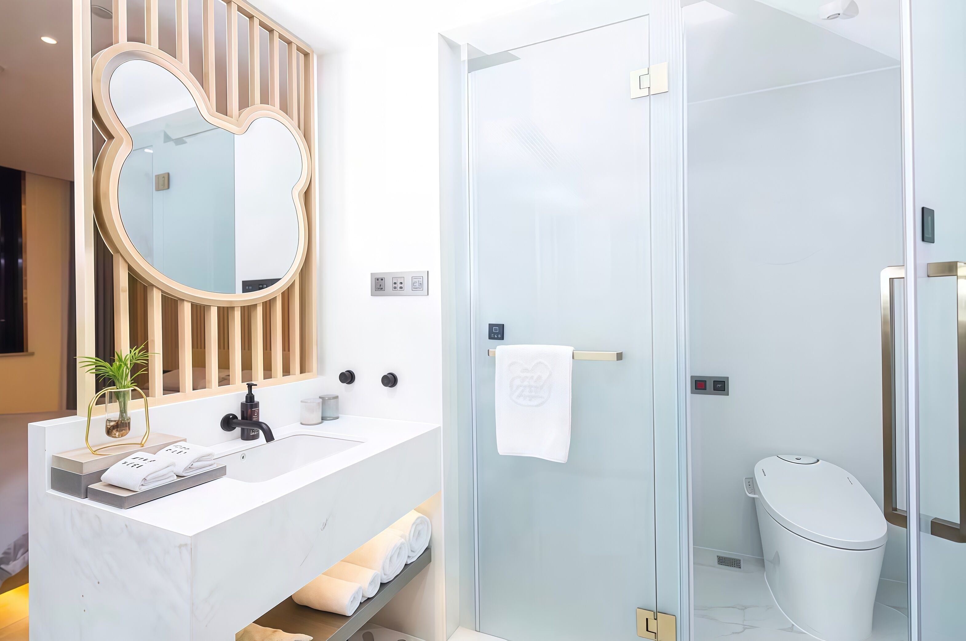 Un baño moderno con un tocador blanco, un espejo grande, cabina de ducha con mampara de cristal y un inodoro.