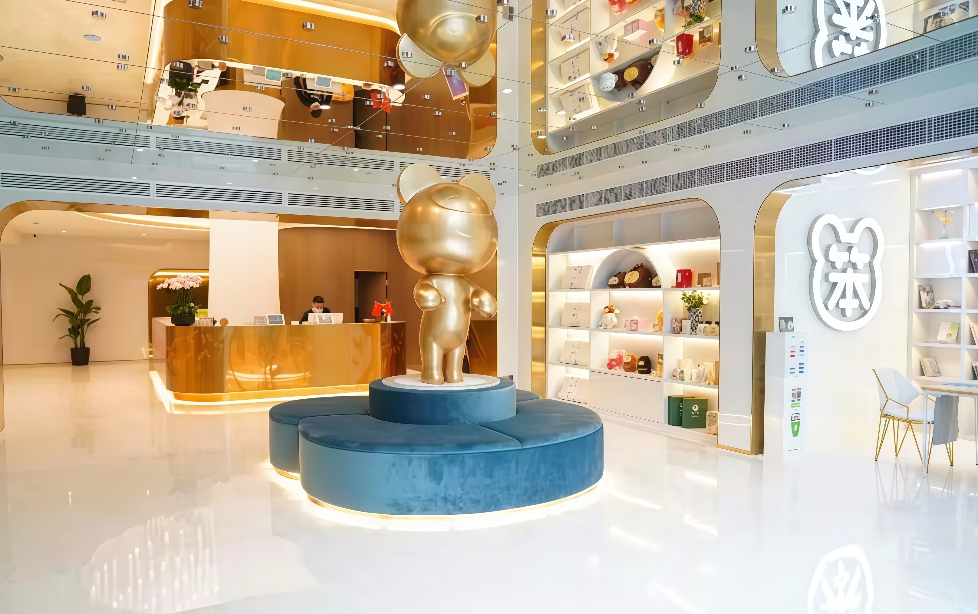 Um lobby de hotel moderno com um balcão de recepção, uma escultura dourada única e um átrio com vários níveis e lojas.