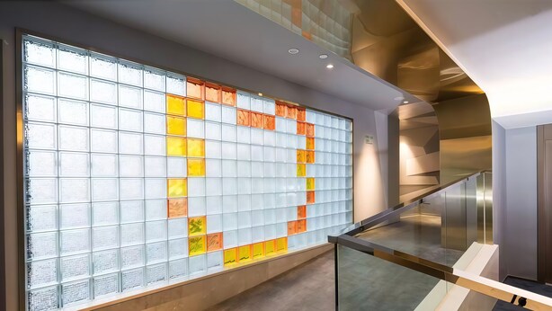 Un interno moderno con ringhiera in vetro, parete decorata e una scala.