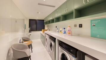 A modern laundry room with a washing machine, dryer, and neatly organized shelves with cleaning supplies.