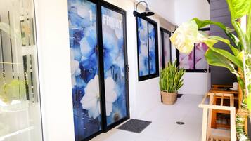 A hallway with glass doors, a potted plant, and a wooden bench.