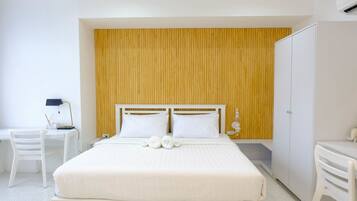 A hotel room with a large bed, a desk, a chair, and a wardrobe.
