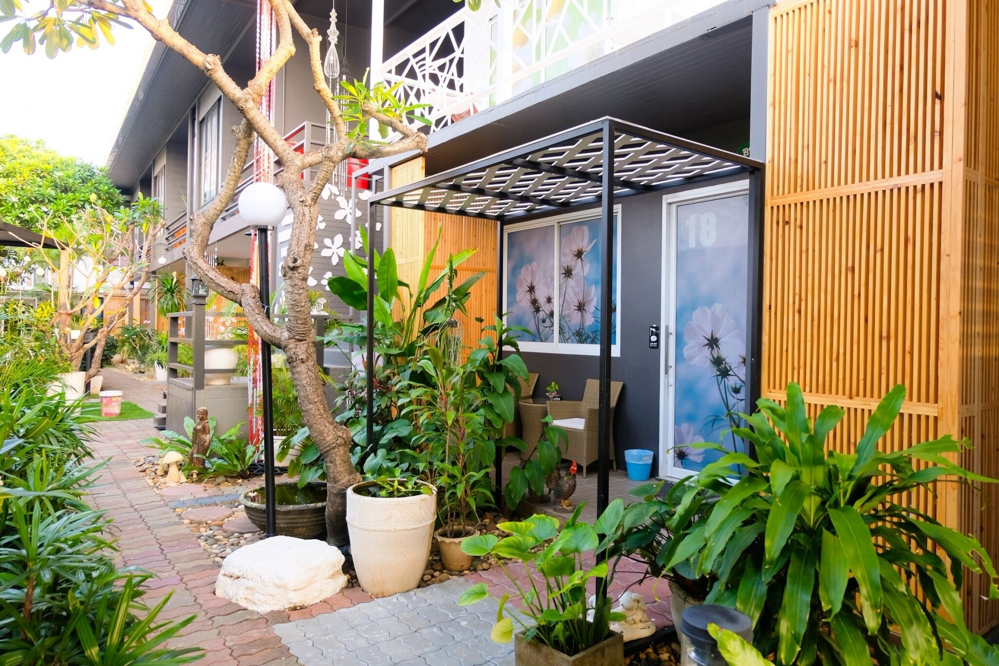 A courtyard with potted plants, a small fountain, and a building with a balcony.