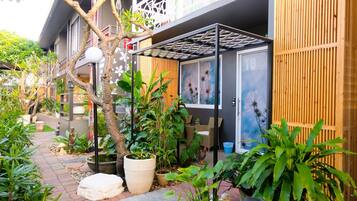 A courtyard with potted plants, a small fountain, and a building with a balcony.