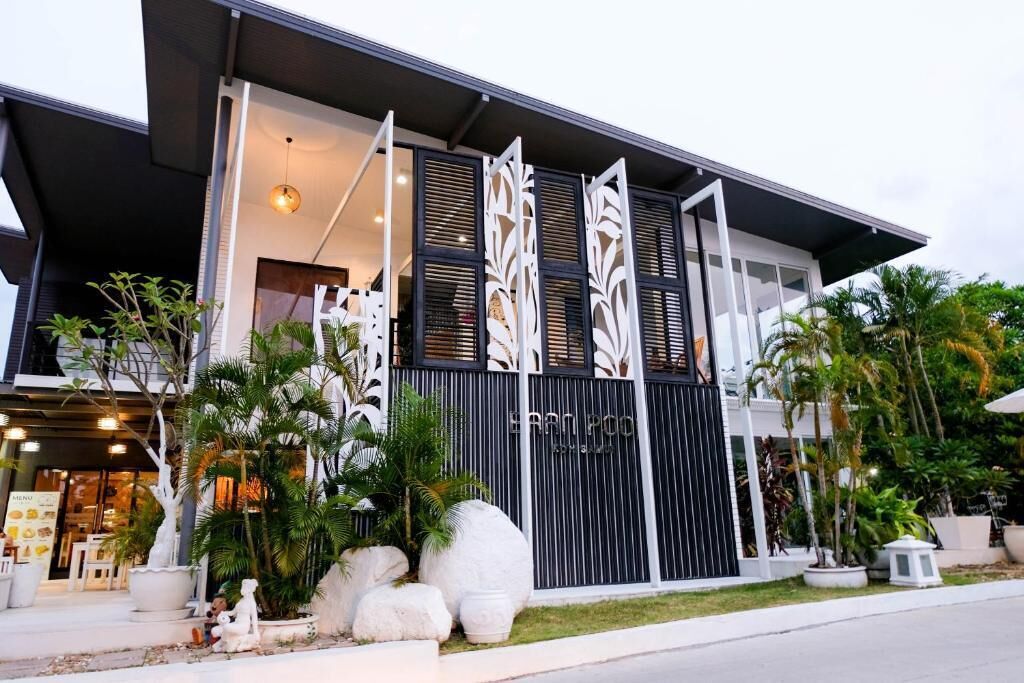 A modern building with a black and white facade, large decorative panels, and a well-maintained garden with palm trees.