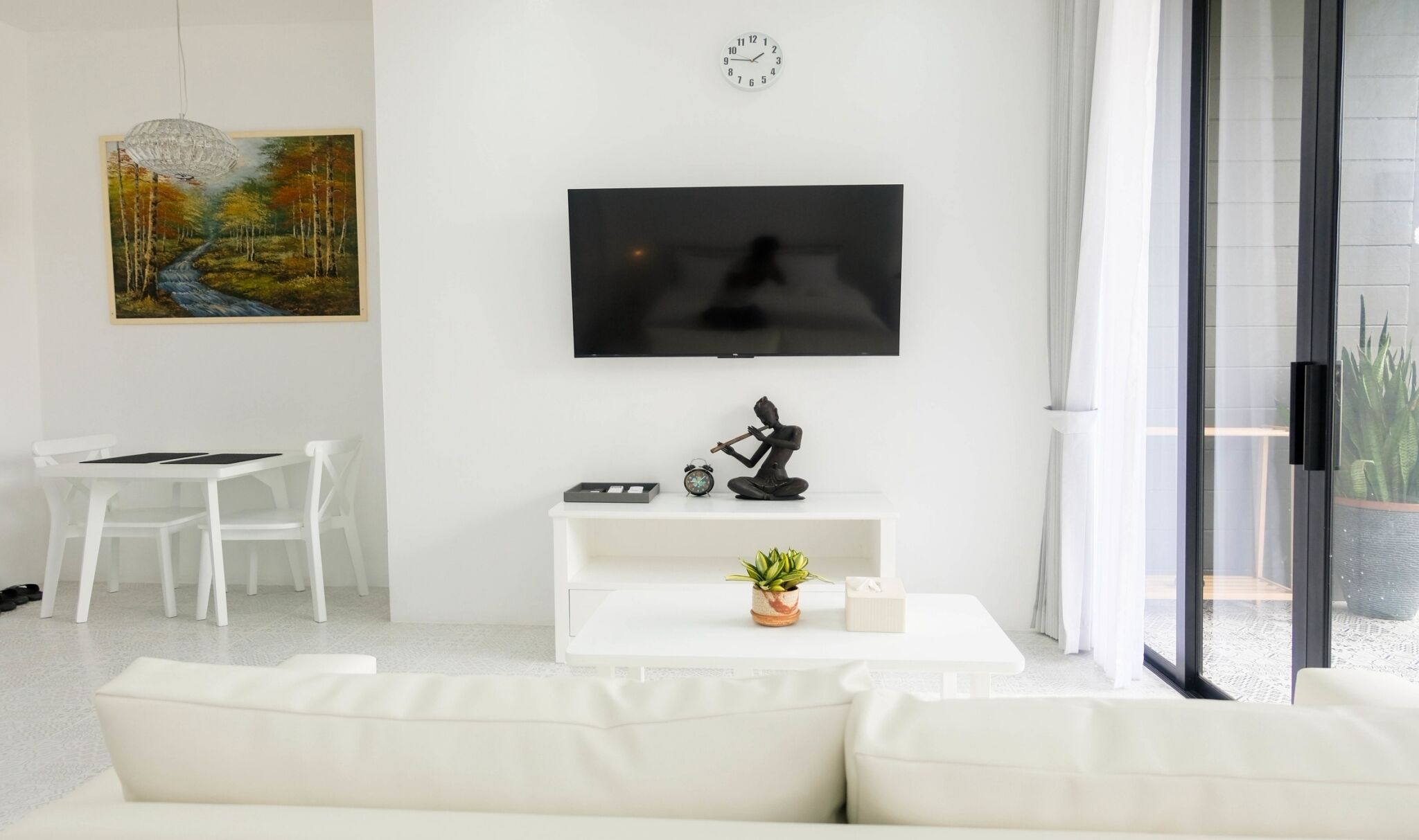 Una sala moderna con un televisor de pantalla plana, un cuadro, una escultura y una planta en maceta.