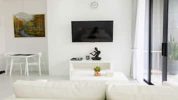 Una sala moderna con un televisor de pantalla plana, un cuadro, una escultura y una planta en maceta.