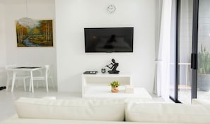 Uma sala de estar moderna com uma televisão de tela plana, um quadro, uma escultura e um vaso com planta.