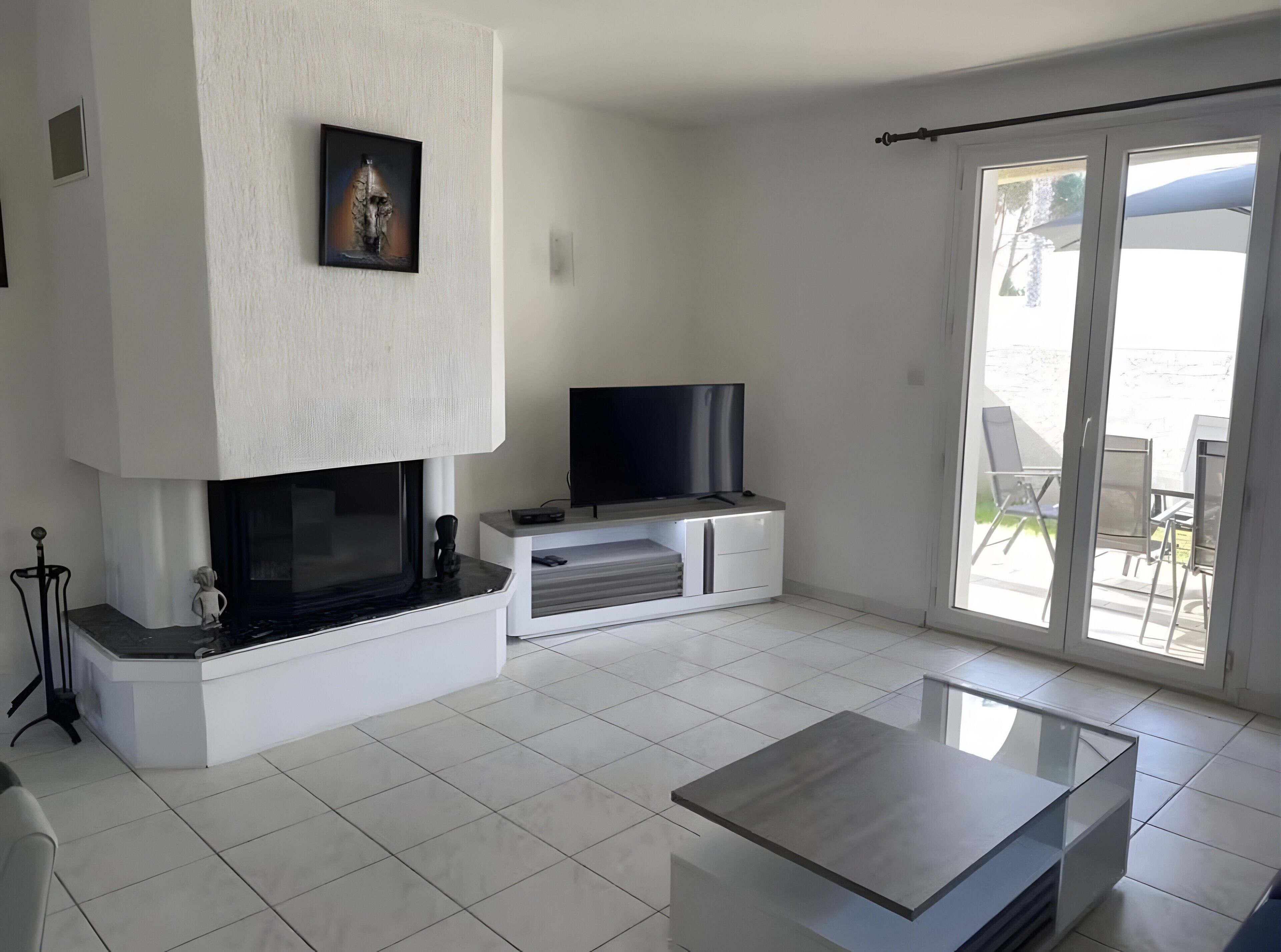 Un salon moderne avec une cheminée, un téléviseur à écran plat et une table basse en verre.