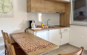 A compact kitchen with wooden cabinets, a built-in dishwasher, and a window with blinds. - Gorgeous apartment in Opric (Opric)
