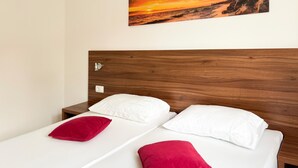 Ein Doppelbett mit Holz Kopfteil, zwei weiße Kissen und zwei rote Kissen.