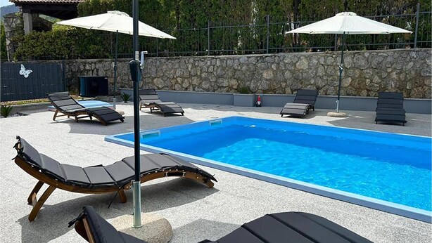 Ein Schwimmbecken mit Liegestühlen und Sonnenschirmen.