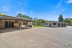 A building with a covered outdoor area, a small adjacent structure, and a paved driveway. - Sleeps 8 on 13 Acres | Pool + 7 Min to CBD (Koongal)
