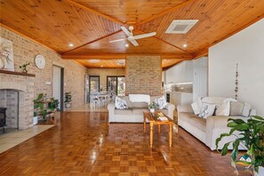 A spacious living area with a wooden floor, a fireplace, and a dining area with white furniture.