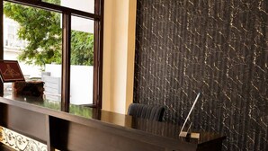 A reception desk with a dark wood finish, a patterned tile design, and a view of greenery outside.