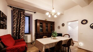 Et spiseområde med et bord, stole, en rød sofa, et skab og en lysekrone.