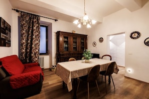 Ein Essbereich mit Tisch, Stühlen, einer roten Couch, einem Schrank und einer Chandelier.