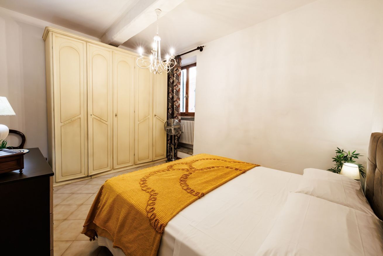 A bedroom with a bed, a wardrobe, a desk, and a lamp.