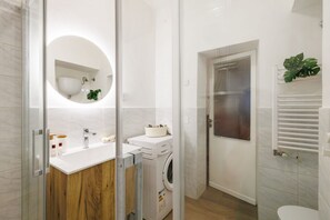 A modern bathroom with a glass shower enclosure, a built-in sink, and a washing machine. - GuestHost - Dimora Camollia in the Heart of Siena (Siena)