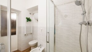 Et moderne badeværelse med en glasafskærmet bruseniche, en bidet og et toilet.