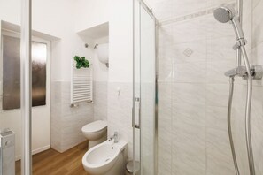 Ein modernes Badezimmer mit einer gläsernen Dusche, einem Bidet und einer Toilette.