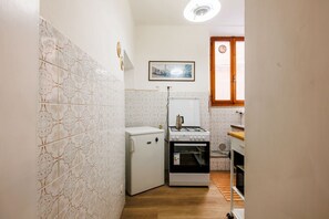 Eine kleine Küche mit Kühlschrank, Herd und Backofen.