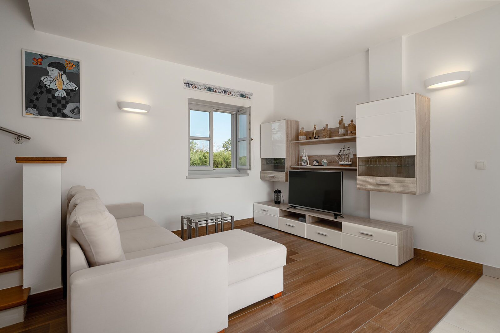 A modern living room with a sofa, TV, and built-in shelves.