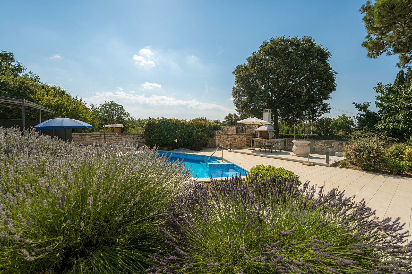Ein Garten mit Schwimmbad, Grillplatz und einer Steinmauer.
