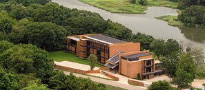 Ein modernes Gebäude mit flachem Dach, umgeben von üppiger Vegetation und einem Fluss.