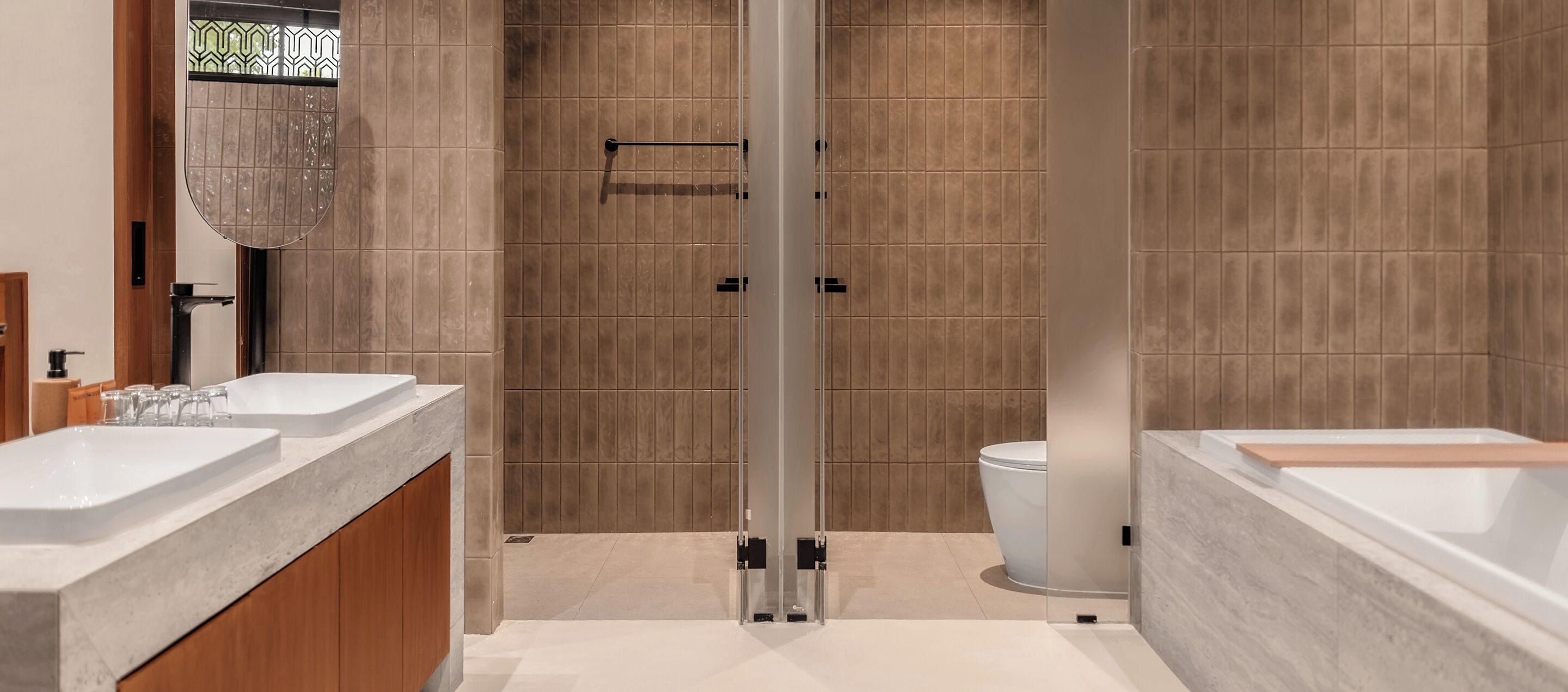 A modern bathroom with two sinks, a shower, and a toilet.