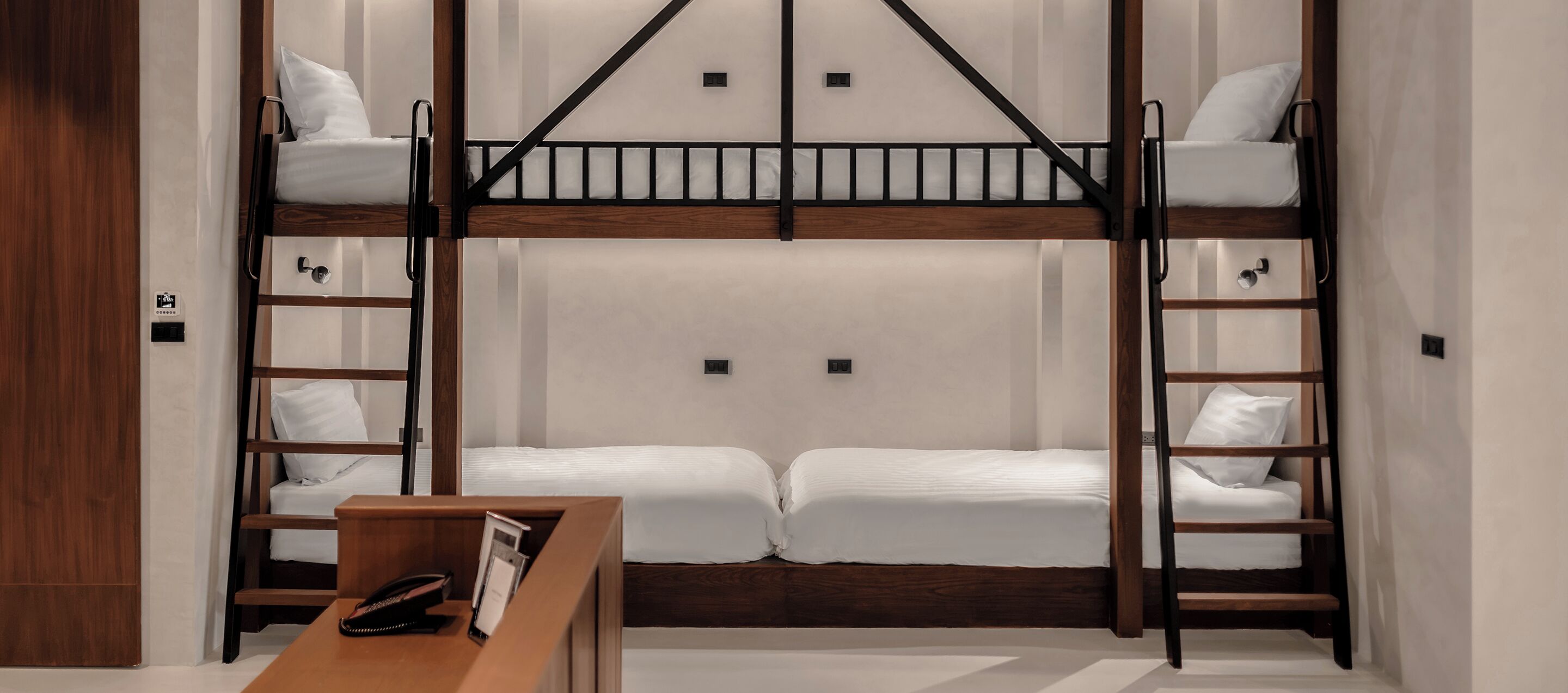 Une chambre avec un lit superposé, une échelle en bois, une table de chevet et un téléphone.