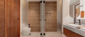 Een moderne badkamer met een houten deur, een glazen douchecabine en een wastafelmeubel met spiegel.