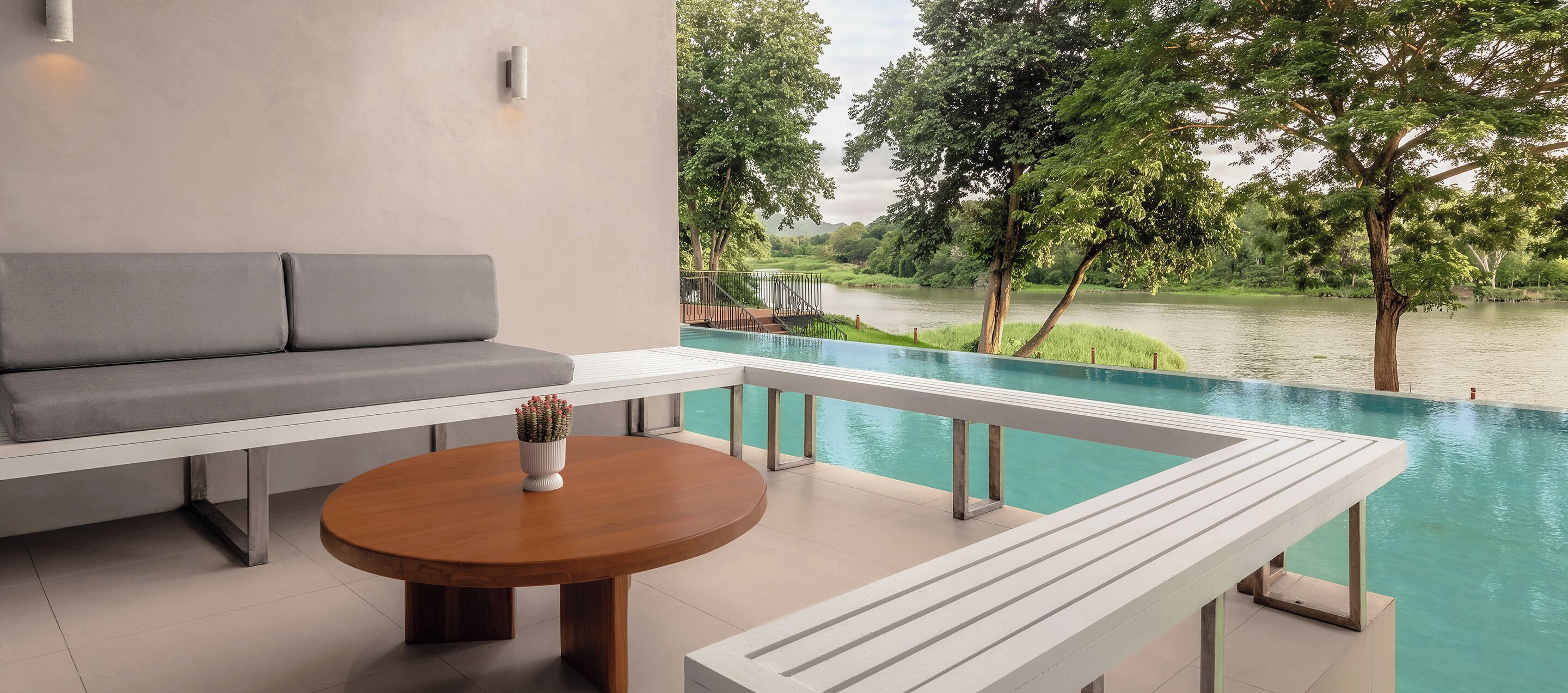 A modern outdoor seating area with a pool, a view of a river, and a garden.