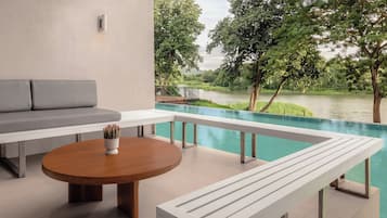A modern outdoor seating area with a pool, a view of a river, and a garden.