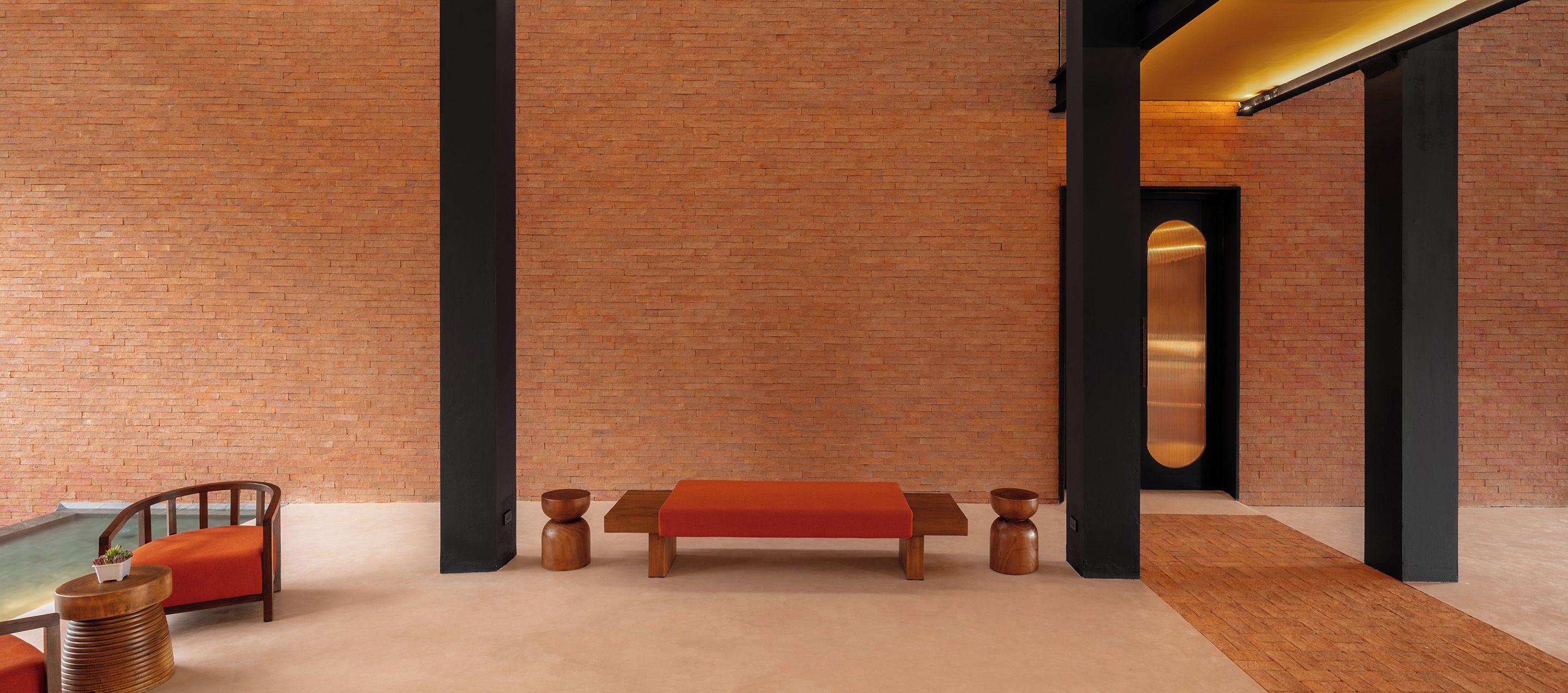 A modern interior with a brick wall, a wooden bench, a table, and a chair.