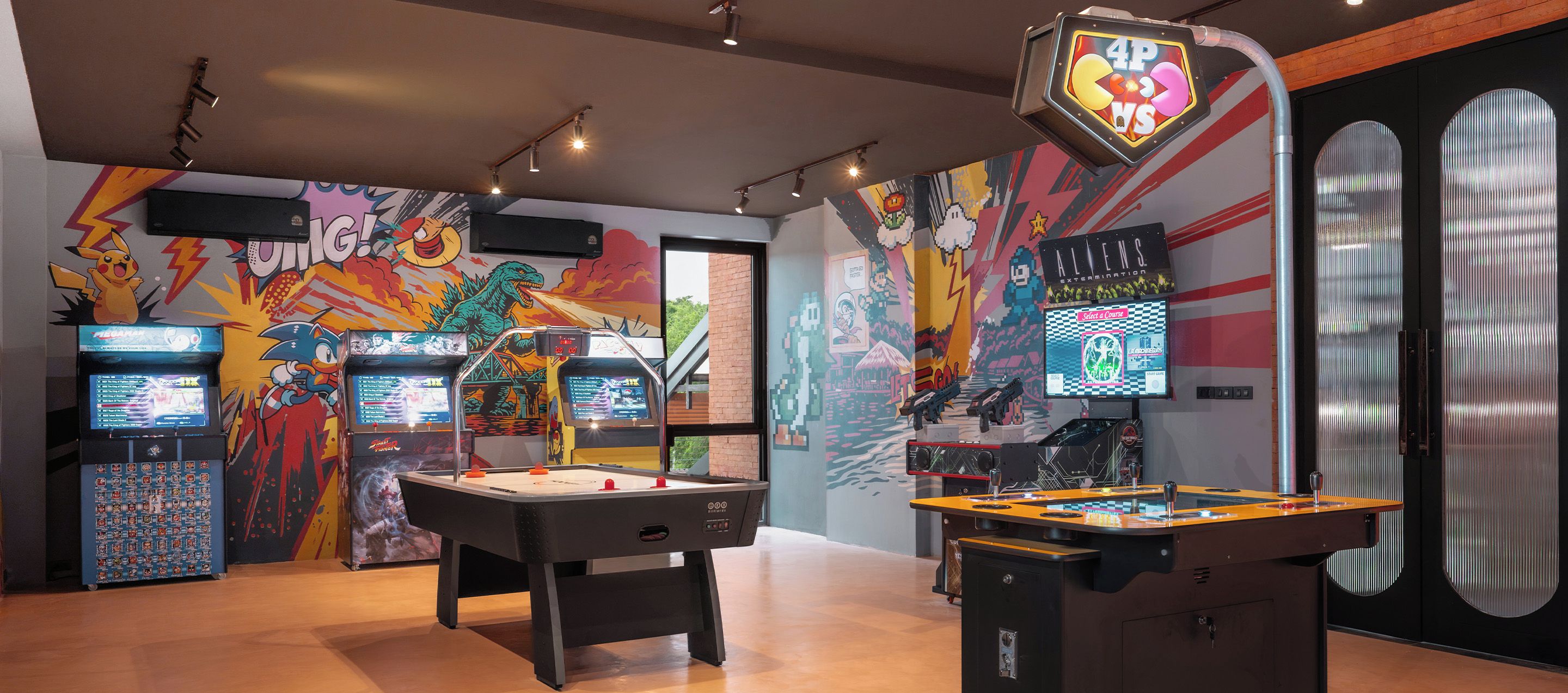 A gaming area with multiple arcade machines, a foosball table, and a selection screen for a racing game.