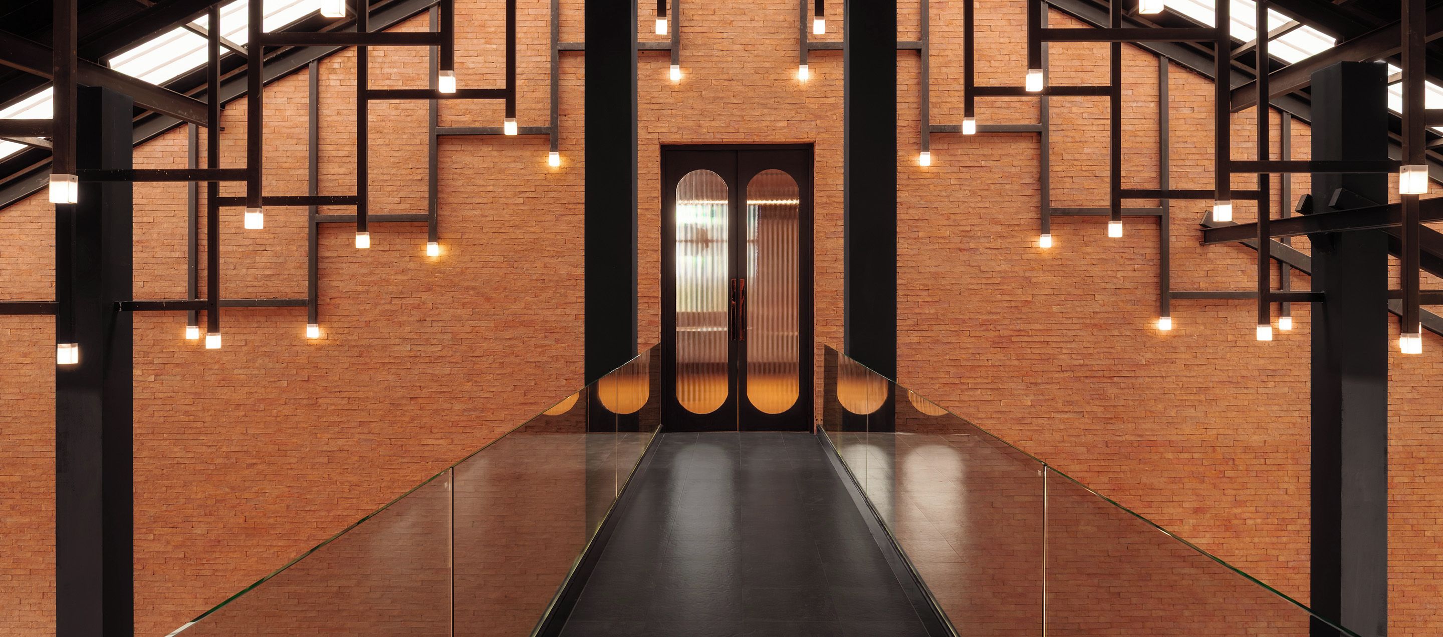 Ein modernes Interieur mit Backsteinwand, einem zentralen Aufzug und einer Glasgalerie.