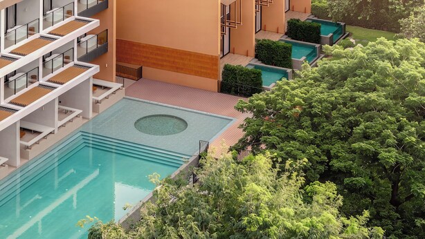 A multi-story hotel with a swimming pool, balconies, and a garden area. - Hykyo River Kwai Hotel (Kanchanaburi)