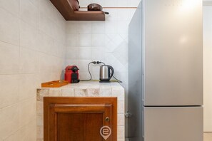 Eine Küche mit Kühlschrank, Wasserkocher und einem roten elektrischen Wasserkocher auf der Arbeitsplatte.