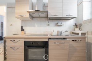 A modern kitchen with light wood cabinetry, a stainless steel sink, and a built-in oven. - Casa Lelia – A special view in the heart of Cagliari 🌅✨ (Cagliari)